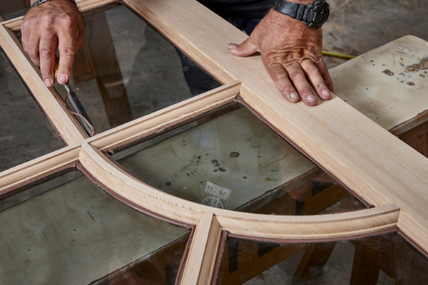 Hands working on a custom window project in the mill shop. 
